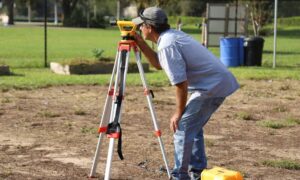 Surveyor marking yard for wall project - ALTA SURVEY Arizona Surveyor setting up equipment in a yard to prepare for a construction staking survey before building a block wall