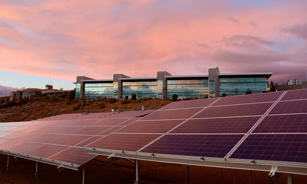 Commercial building with a large solar panel installation covering part of the surrounding property under a clear evening sky