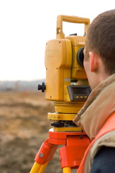 Land survey expert using total station equipment to perform a boundary line survey after flooding
