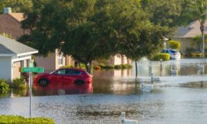 Flooded residential street with cars and houses surrounded by water, showing why homeowners need an elevation certificate