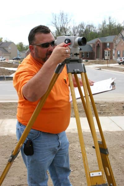 Licensed land surveyor using equipment to measure property elevation for an elevation certificate
