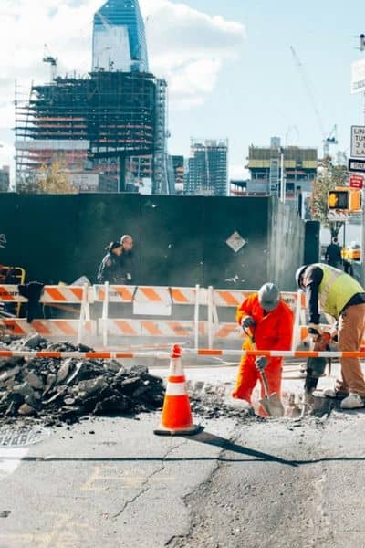 Workers doing road construction in a busy urban job site